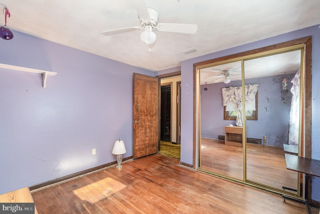 unfurnished bedroom with a ceiling fan, baseboards, wood finished floors, visible vents, and a closet