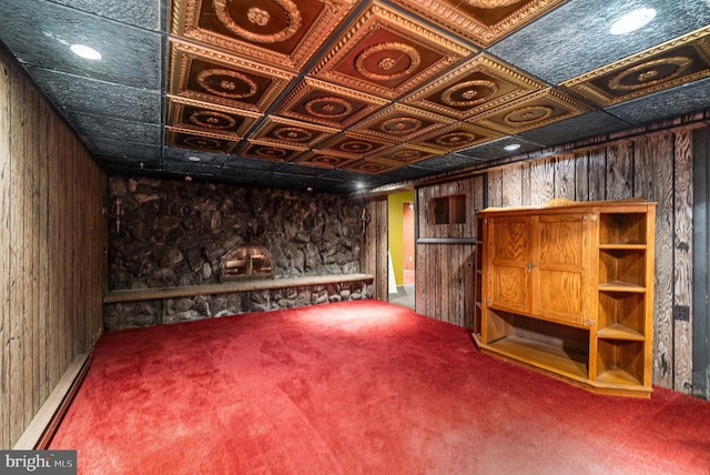 finished below grade area with an ornate ceiling, wood walls, a baseboard heating unit, and carpet flooring