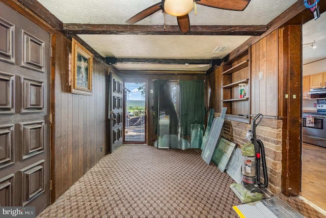 interior space featuring visible vents, carpet, wooden walls, and beamed ceiling