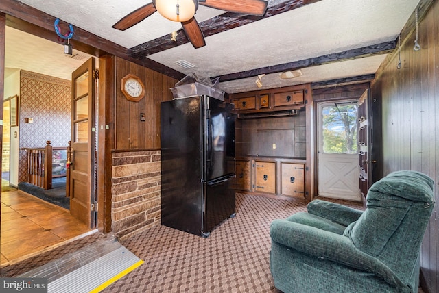 carpeted living area with ceiling fan, a textured ceiling, visible vents, wood walls, and beamed ceiling