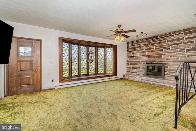 unfurnished living room featuring a stone fireplace, a ceiling fan, carpet, and a baseboard heating unit