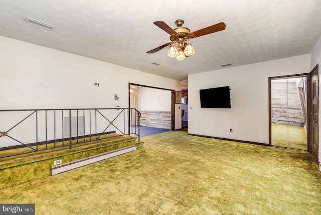 interior space with ceiling fan, a baseboard heating unit, carpet, and visible vents