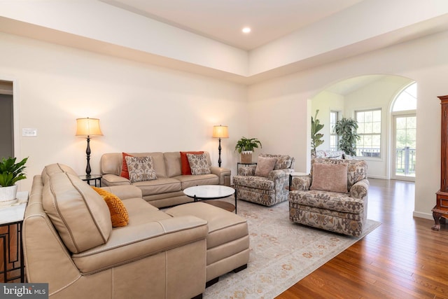 living area featuring arched walkways, baseboards, recessed lighting, and wood finished floors