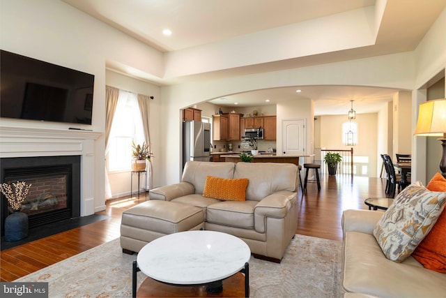 living area featuring light wood-style floors, arched walkways, and a wealth of natural light