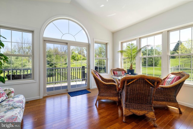sunroom featuring plenty of natural light, a deck, vaulted ceiling, and hardwood / wood-style floors