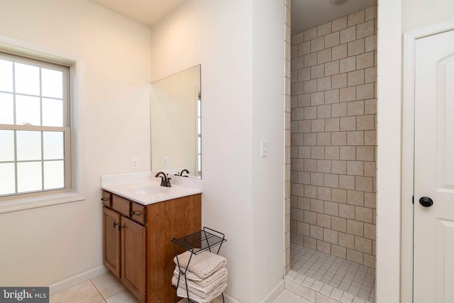 full bath featuring tile patterned floors, a tile shower, baseboards, and vanity