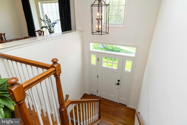 entrance foyer featuring a high ceiling, a chandelier, a healthy amount of sunlight, and wood finished floors