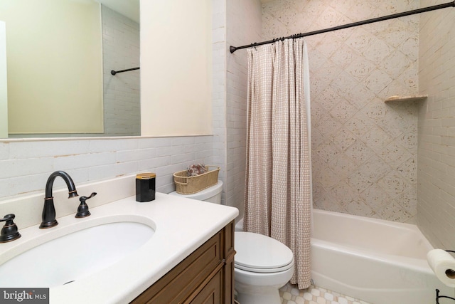 bathroom with vanity, toilet, tile walls, and shower / tub combo