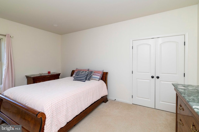bedroom with baseboards, light carpet, and a closet
