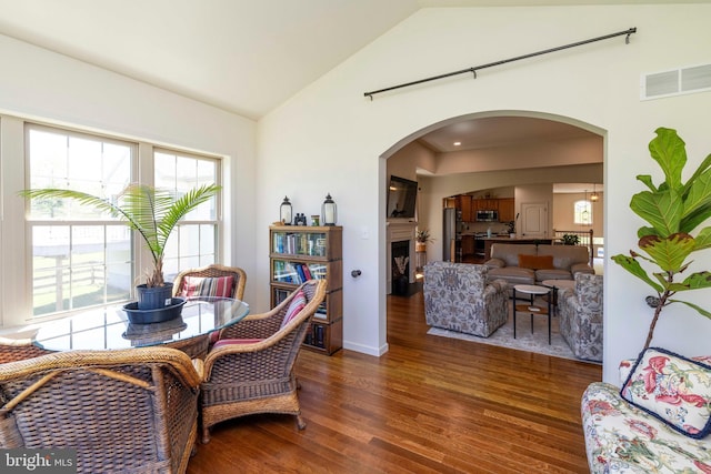 dining area featuring arched walkways, high vaulted ceiling, visible vents, and wood finished floors