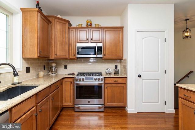 kitchen featuring a sink, backsplash, brown cabinets, and stainless steel appliances