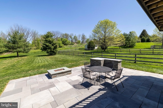 view of patio / terrace with outdoor dining area, a rural view, a fire pit, and fence private yard