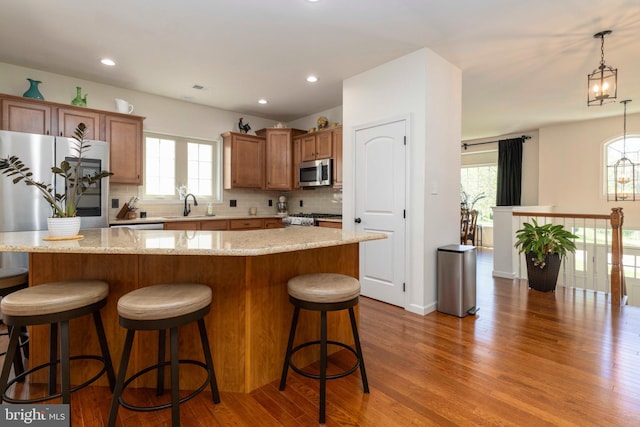 kitchen featuring tasteful backsplash, refrigerator, wood finished floors, a sink, and stainless steel microwave