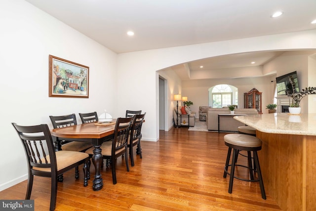 dining room featuring recessed lighting, arched walkways, and light wood-style flooring
