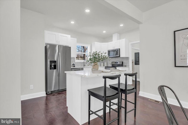 605 Northside Ave, Richmond, VA 23222 - kitchen with visible vents, a breakfast bar, white cabinets, appliances with stainless steel finishes, and backsplash