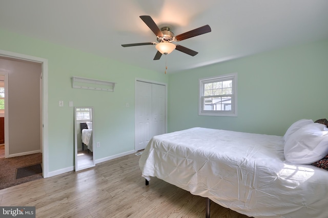 bedroom with ceiling fan, baseboards, wood finished floors, visible vents, and a closet
