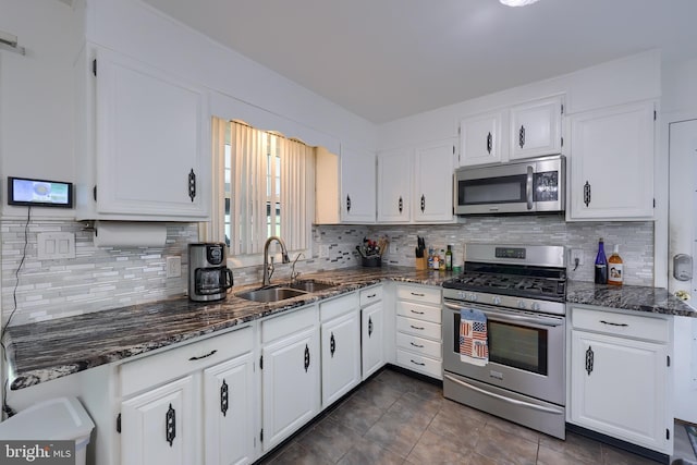 kitchen with a sink, dark stone countertops, white cabinets, and stainless steel appliances