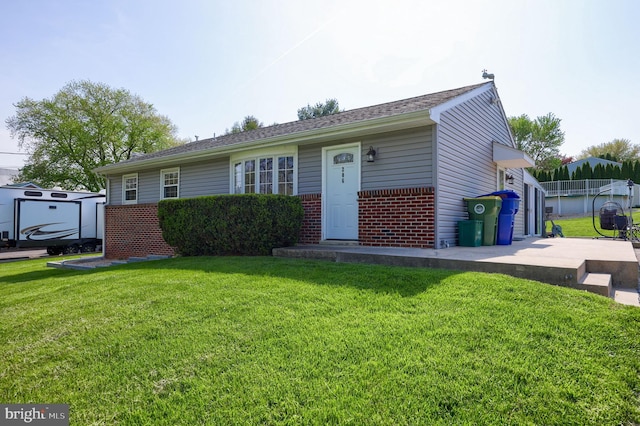 single story home with an outbuilding, a front lawn, a shed, and brick siding