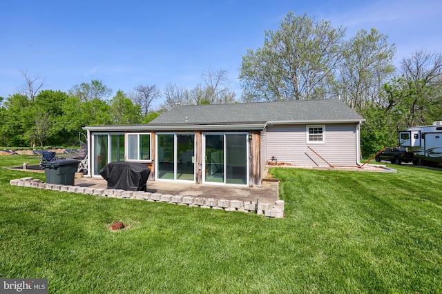 back of property with a lawn, a patio area, and roof with shingles