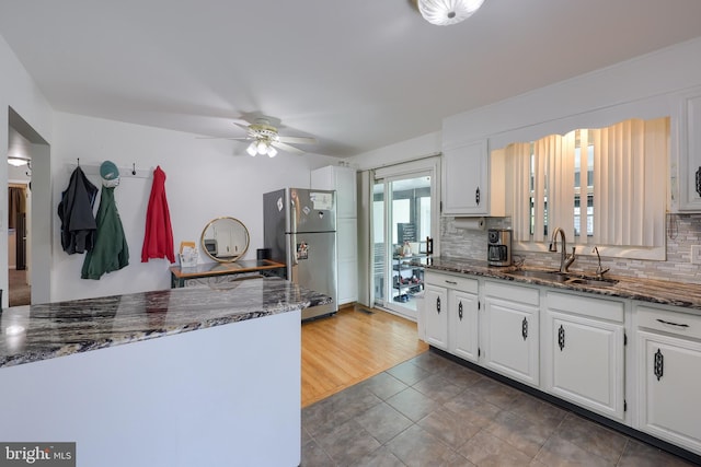 kitchen with freestanding refrigerator, white cabinets, decorative backsplash, and a sink