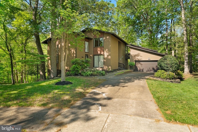 mid-century modern home featuring an attached garage, stucco siding, driveway, and a front yard