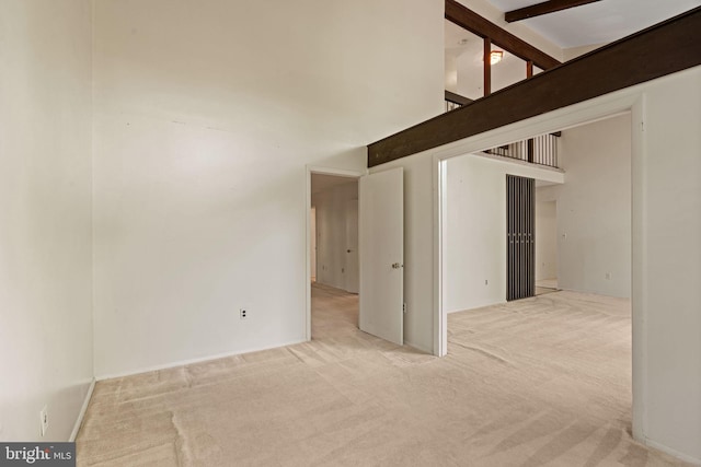 spare room featuring stairs, a high ceiling, and carpet