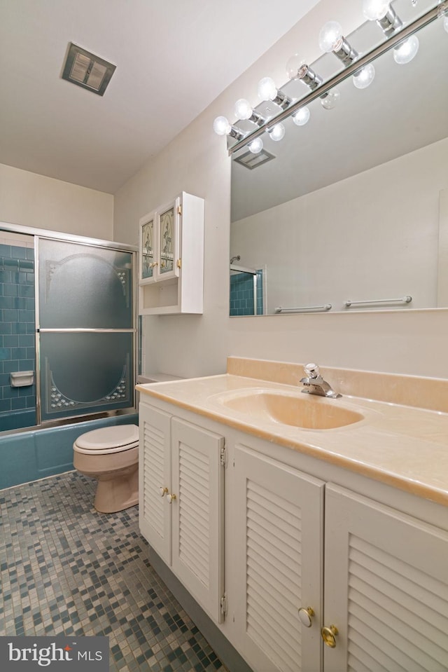 full bath featuring vanity, combined bath / shower with glass door, visible vents, and toilet