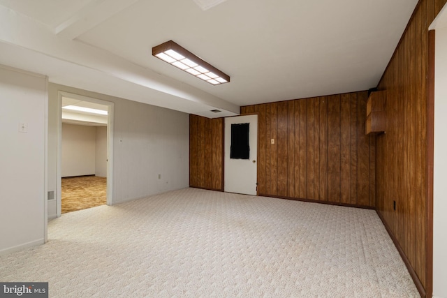 spare room with light colored carpet and wood walls