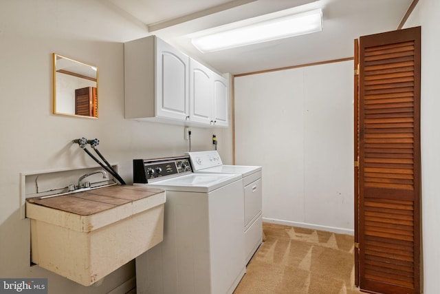 laundry area with washing machine and clothes dryer, cabinet space, a sink, baseboards, and light carpet