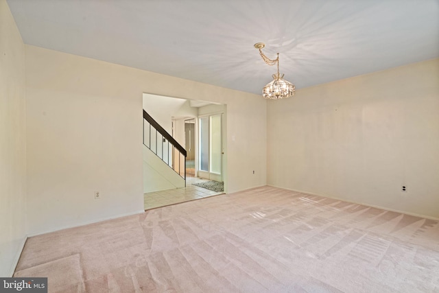 empty room with carpet floors, a chandelier, and stairway