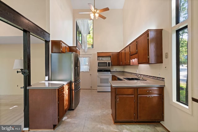 kitchen with a sink, a high ceiling, appliances with stainless steel finishes, and ceiling fan