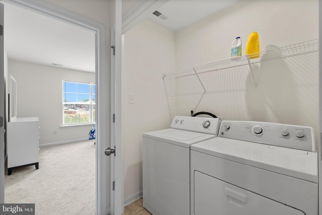 laundry room featuring laundry area, visible vents, light colored carpet, washing machine and clothes dryer, and baseboards