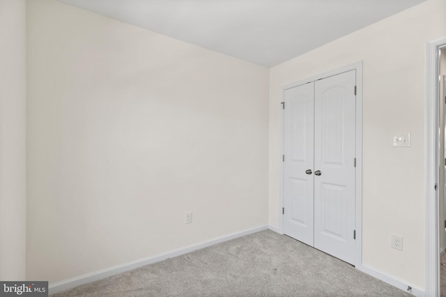 unfurnished bedroom featuring baseboards, carpet, and a closet