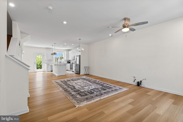 living room with recessed lighting, baseboards, ceiling fan with notable chandelier, and light wood-type flooring