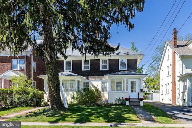 view of front of house with a shingled roof and a front lawn