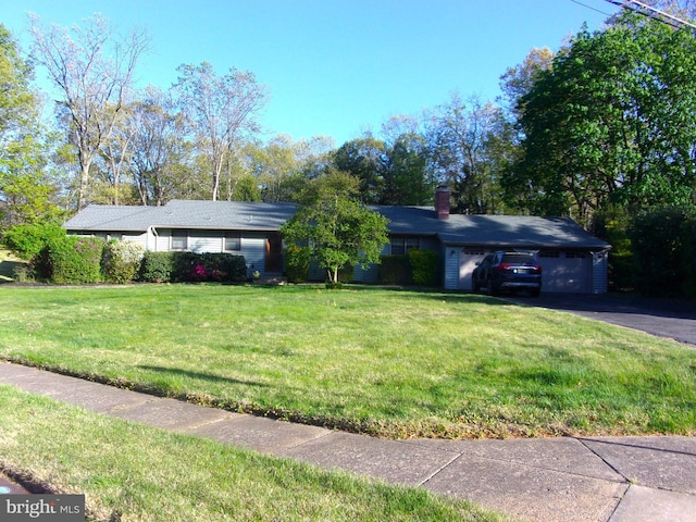 ranch-style home with an attached garage, driveway, a chimney, and a front yard