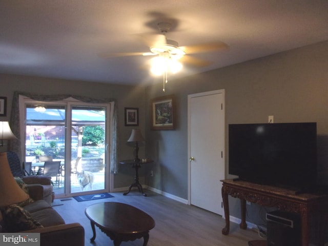 living room featuring baseboards, ceiling fan, and wood finished floors