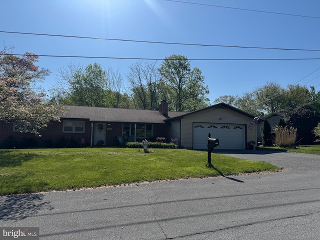 single story home with a front lawn, a chimney, brick siding, an attached garage, and driveway