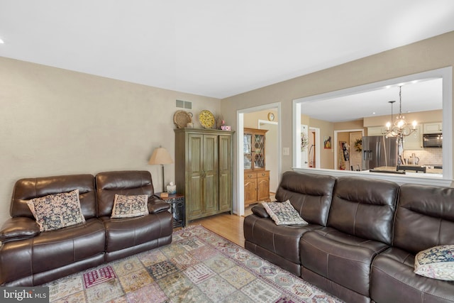 living area featuring visible vents, light wood-style flooring, and a chandelier