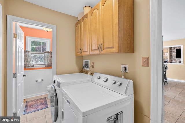 laundry area with baseboards, cabinet space, washing machine and dryer, and light tile patterned flooring