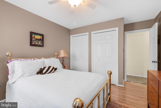 bedroom featuring a ceiling fan, baseboards, multiple closets, and light wood-type flooring