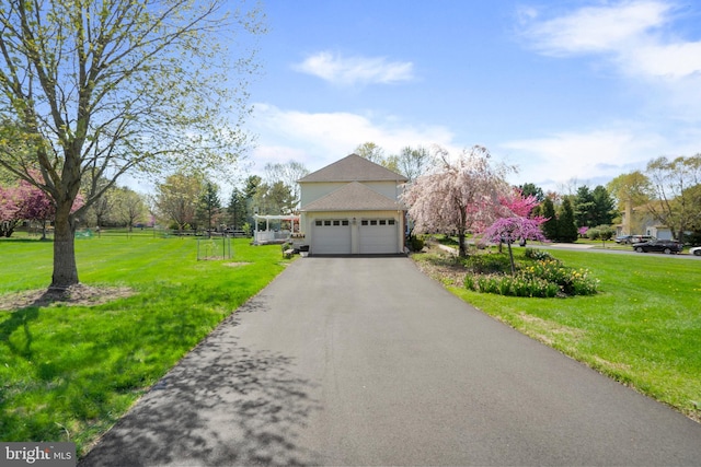 view of front facade with an attached garage, aphalt driveway, fence, and a front yard