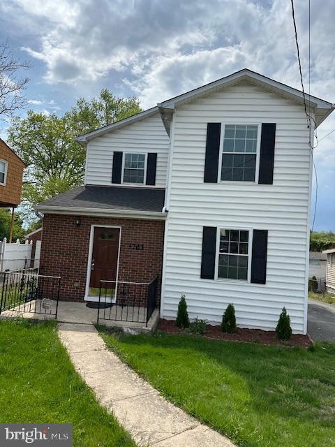 traditional home with brick siding, fence, and a front yard