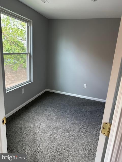 carpeted spare room featuring baseboards