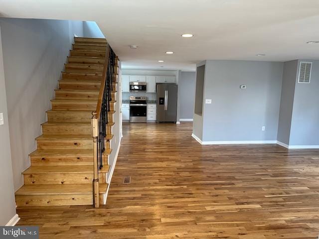 stairs featuring recessed lighting, baseboards, visible vents, and wood finished floors