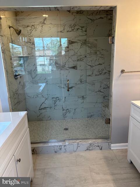 bathroom featuring vanity and a marble finish shower
