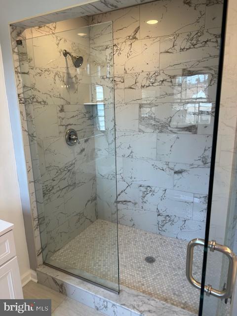bathroom featuring vanity, baseboards, and a stall shower