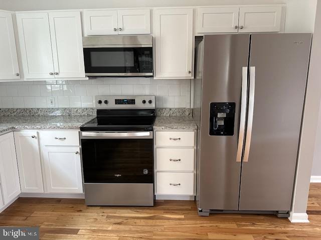 kitchen featuring light stone counters, light wood-style flooring, stainless steel appliances, and white cabinetry