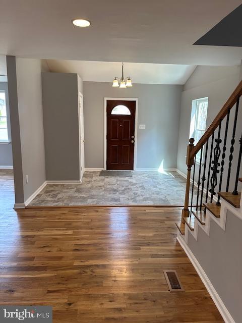 entryway featuring stairway, baseboards, wood finished floors, and a notable chandelier