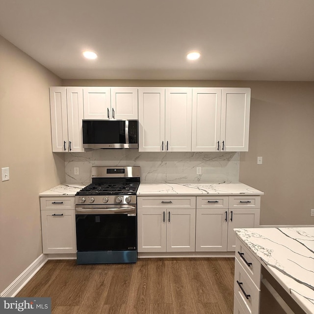 kitchen featuring white cabinetry, appliances with stainless steel finishes, dark wood-style floors, and tasteful backsplash